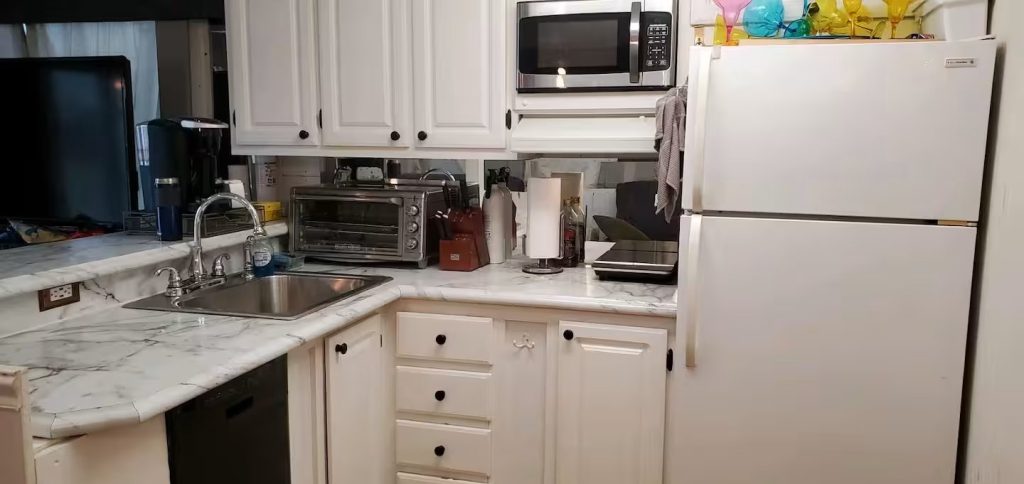 Fully equipped private houseboat kitchen with white cabinetry and appliances