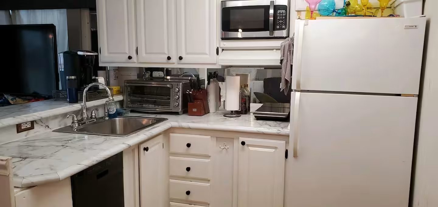 Fully equipped private houseboat kitchen with white cabinetry and appliances