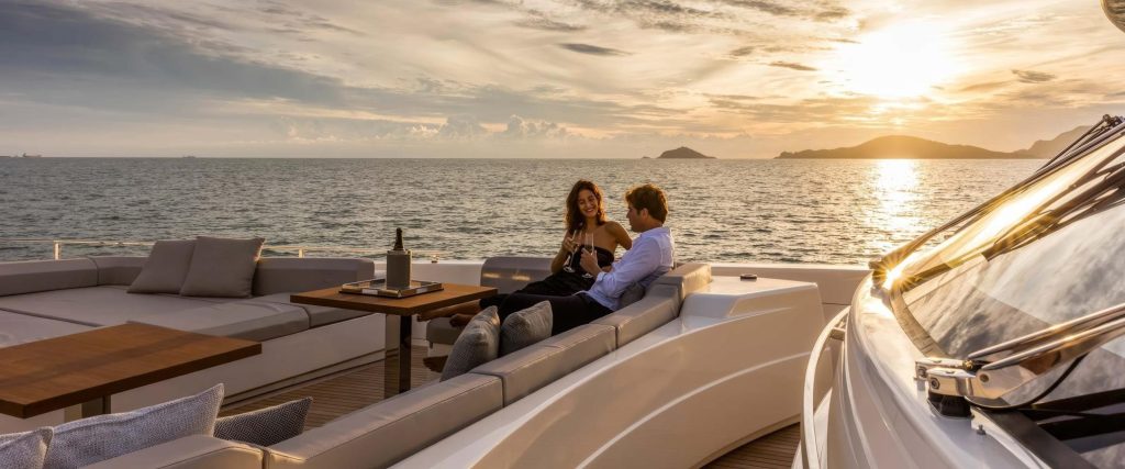 Couple sipping champagne on a spacious luxury yacht lounge deck at sunset