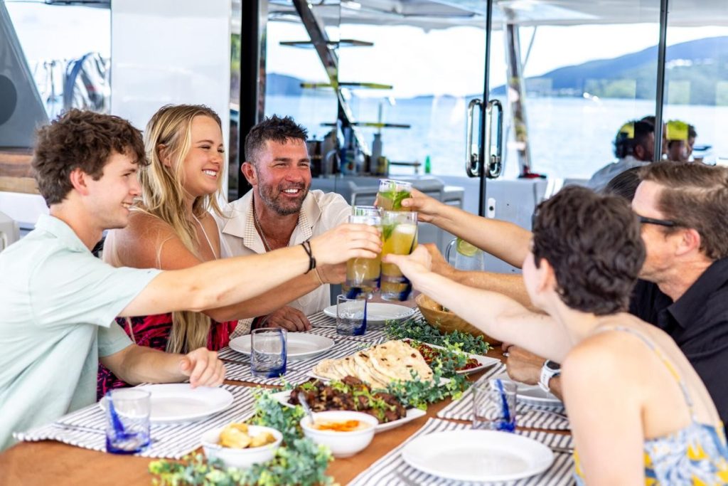 Friends toasting with drinks and enjoying a meal together on a private yacht